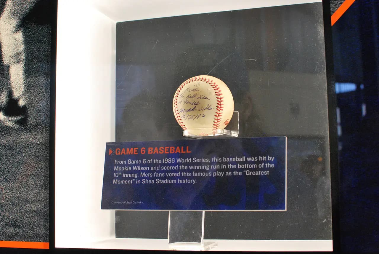 A signed, scuffed baseball in a lit display case above a label reading 'Game 6 Baseball' at the Mets Hall of Fame