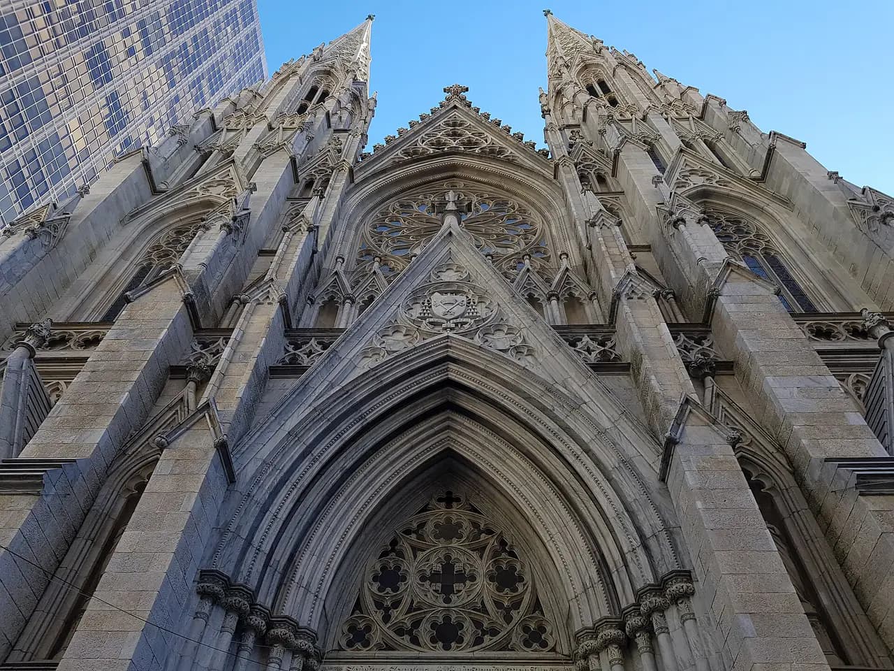 The Gothic stone facade and twin spires of St. Patrick's Cathedral on Fifth Avenue, seen from below