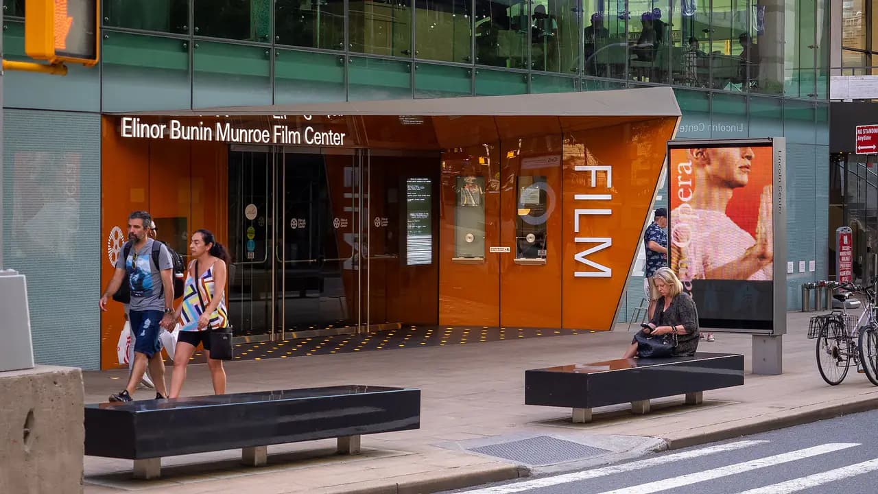 The orange-lit glass entrance of Film at Lincoln Center's Elinor Bunin Munroe Film Center on West 65th Street