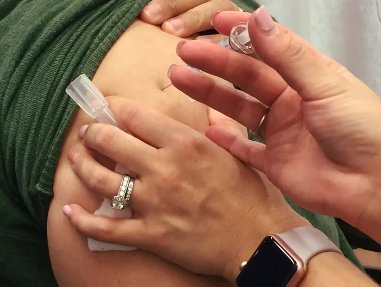 A woman receives a seasonal flu shot in her upper arm