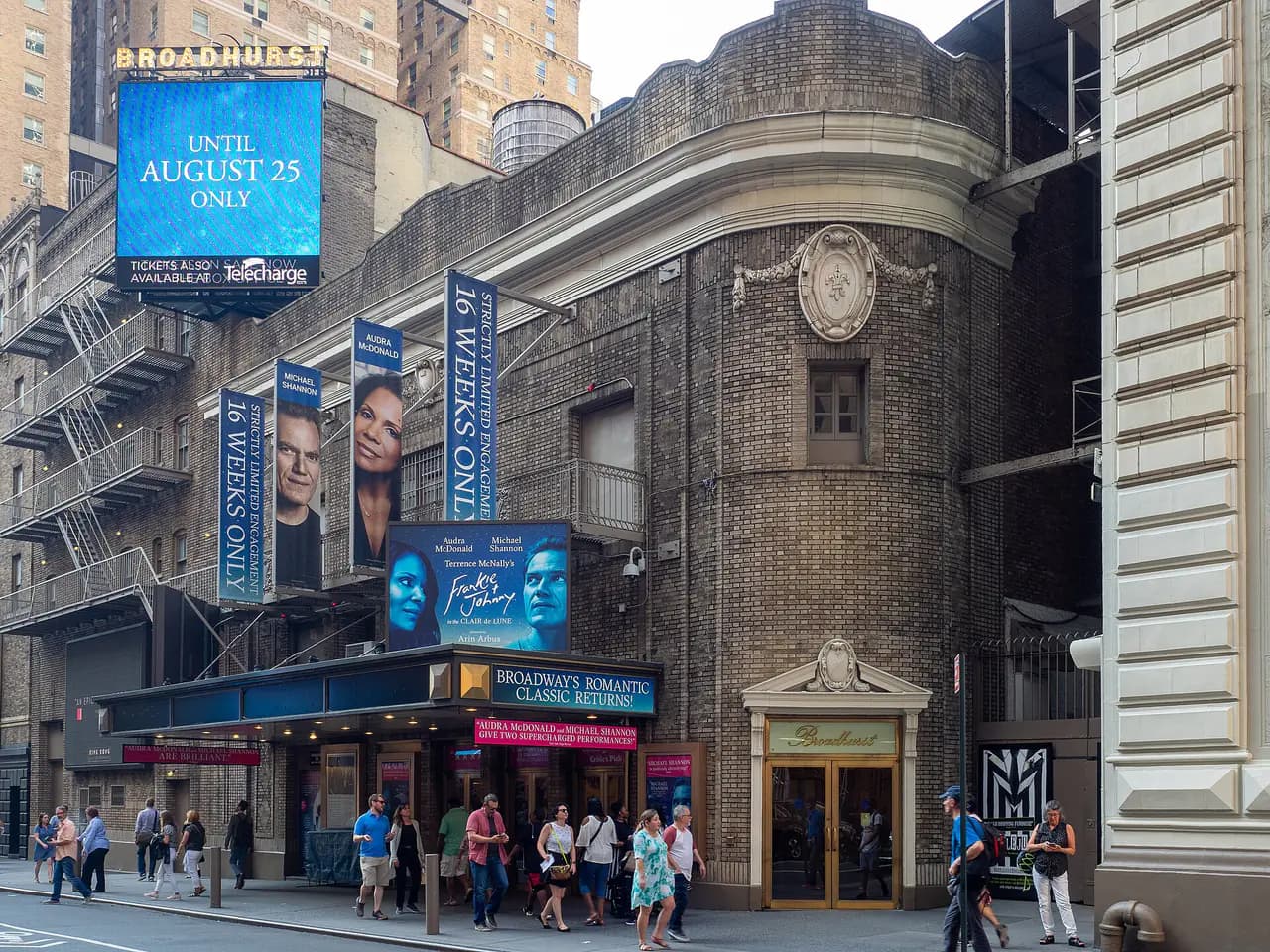 The brick facade and marquee of the Broadhurst Theatre on West 44th Street, with pedestrians on the sidewalk