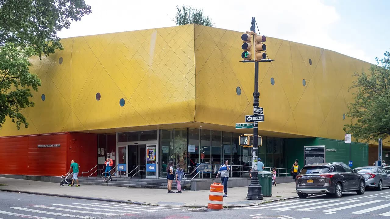 The yellow, tile-covered Brooklyn Children's Museum building with its red base and glass entrance on Brooklyn Avenue in Crown Heights