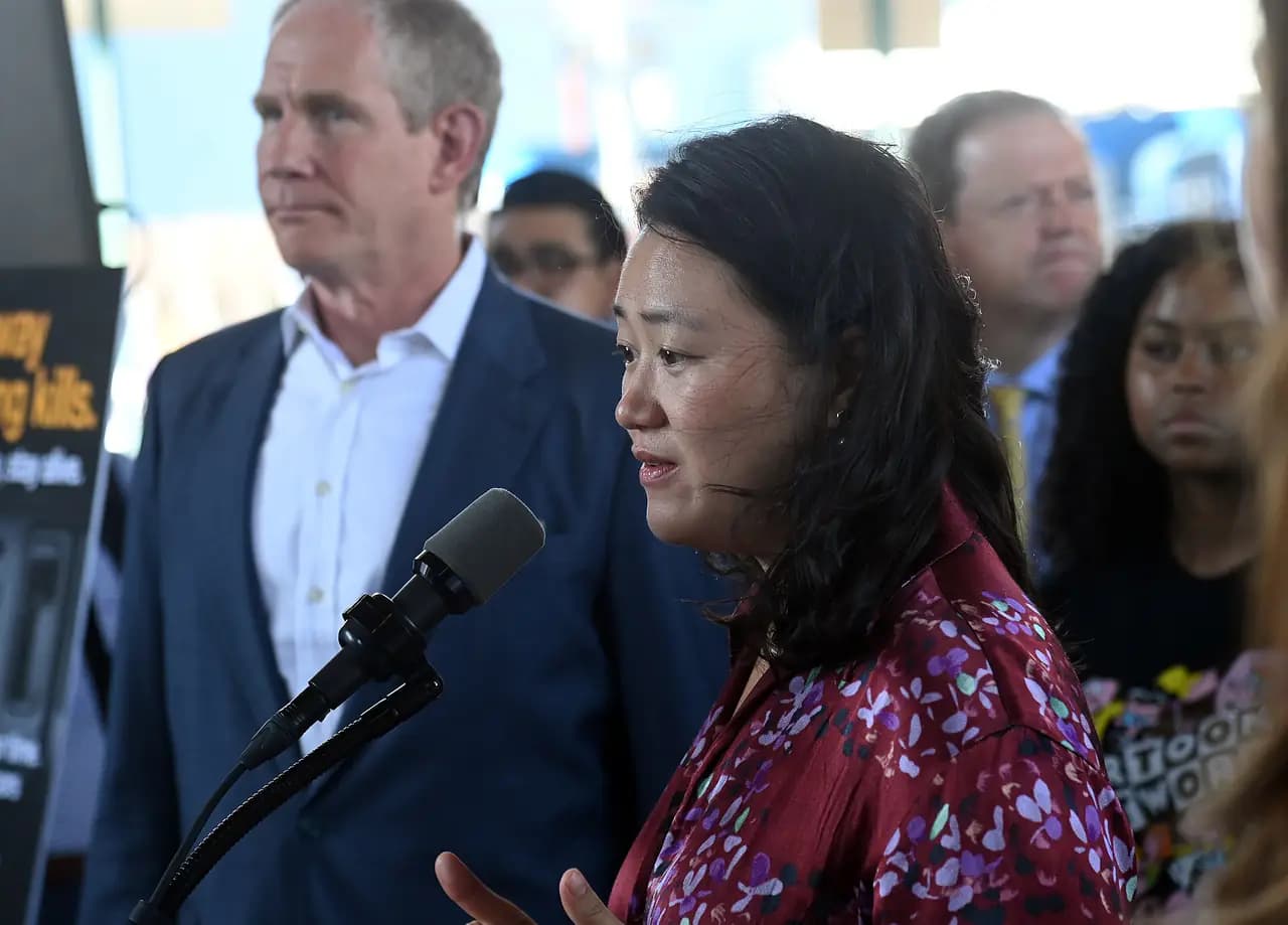 Council Member Julie Won speaking into a microphone at an outdoor press event in Queens