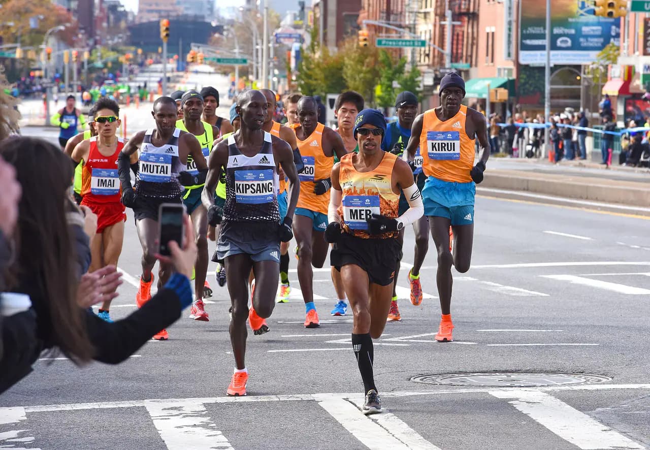 Lead pack of marathon runners on a closed Fourth Avenue in Brooklyn, with spectators behind barricades