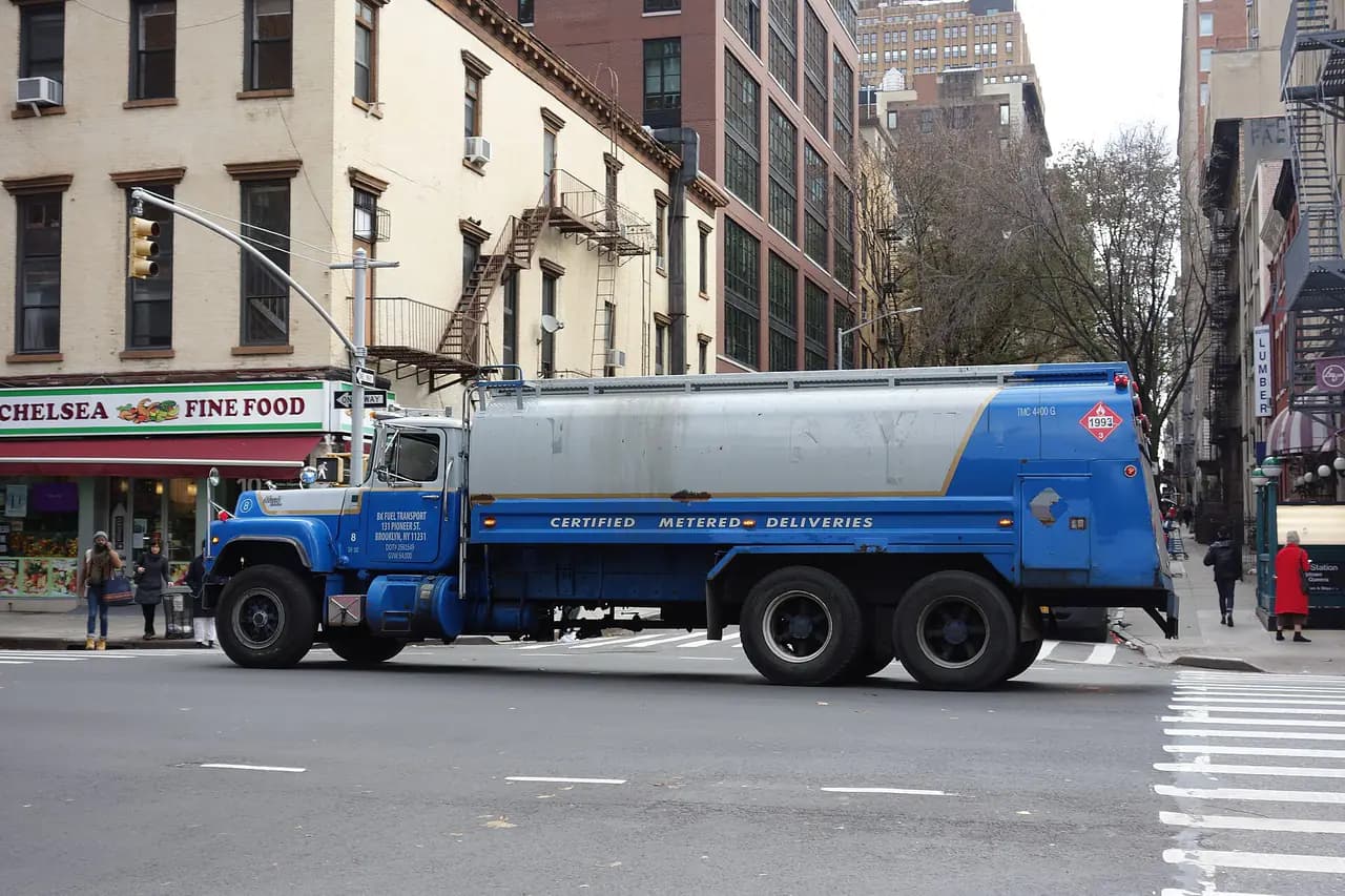 A blue fuel delivery tanker truck marked Certified Metered Deliveries on Eighth Avenue at West 25th Street