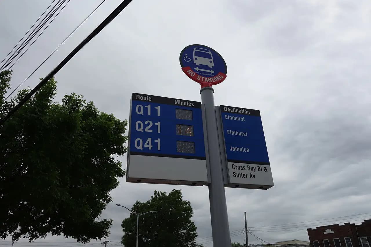 A pole-mounted bus countdown clock listing the Q11, Q21 and Q41 routes at a Queens bus stop