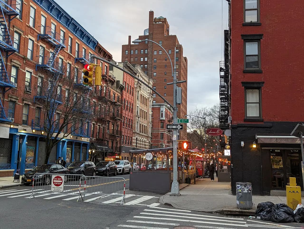 Avenue B in the East Village with brick walk-up buildings, street trees and a crosswalk