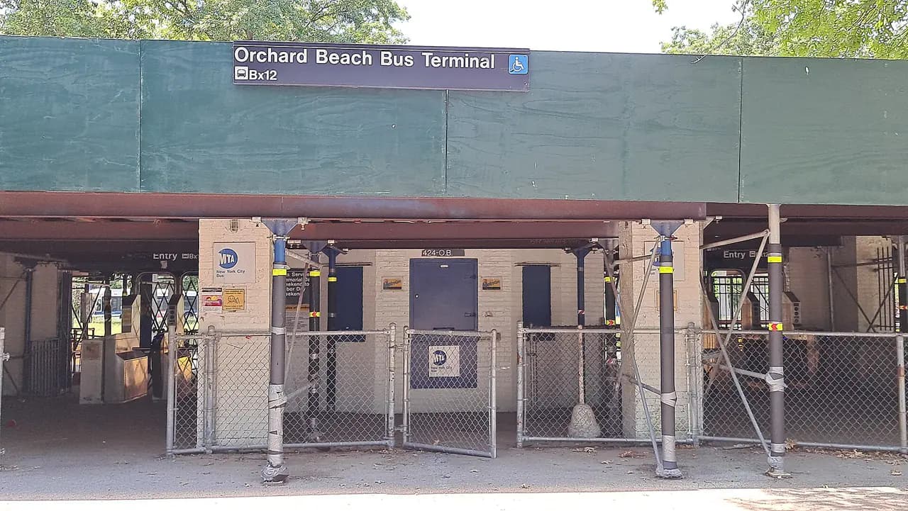 The fenced-off Orchard Beach bus terminal in Pelham Bay Park, with a green canopy and closed entrances