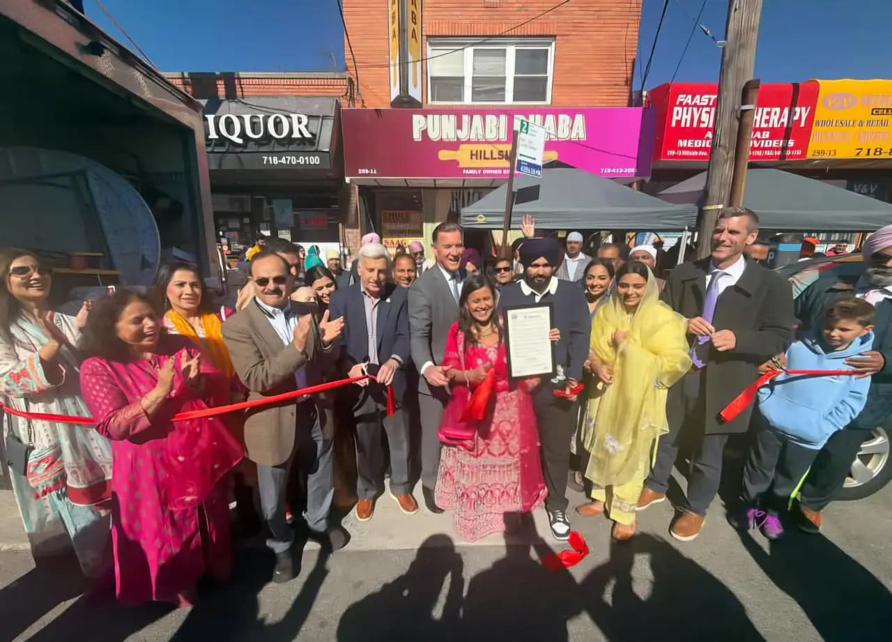 Owner Navdeep Singh holds a proclamation with Queens elected officials and family members at the red-ribbon cutting outside the pink Punjabi Dhaba storefront on Hillside Avenue