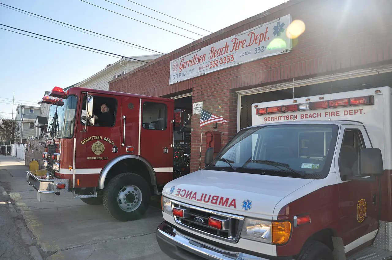 A red fire engine and a white ambulance parked outside the brick Gerritsen Beach Fire Department firehouse in Brooklyn