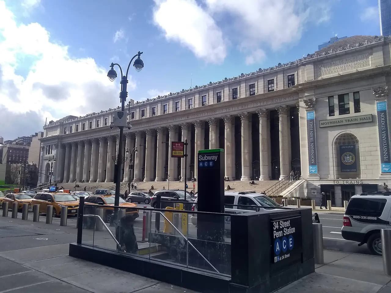 The colonnaded Eighth Avenue facade of the Farley Building, home of Moynihan Train Hall, with a subway entrance in the foreground