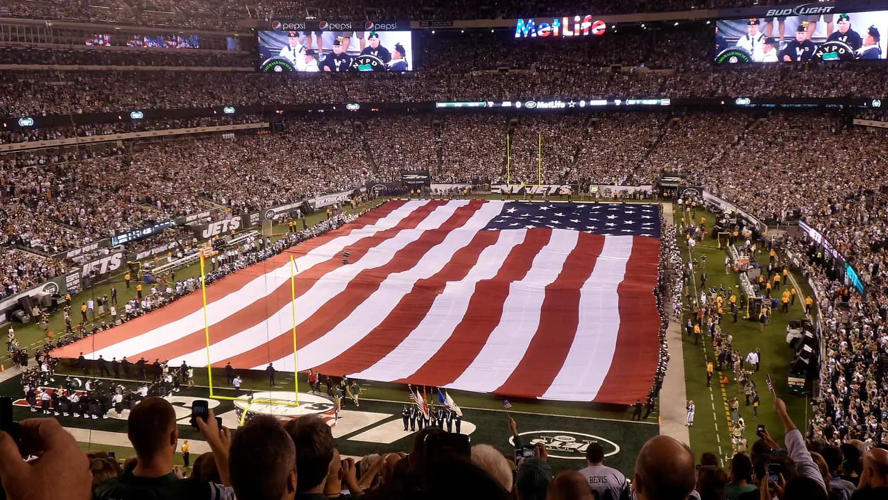 A huge American flag covers the field at a packed MetLife Stadium before a New York Jets home game