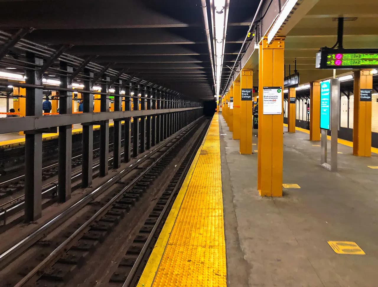Empty platform with orange columns and yellow tactile edge at the Franklin Avenue-Medgar Evers College subway station in Crown Heights