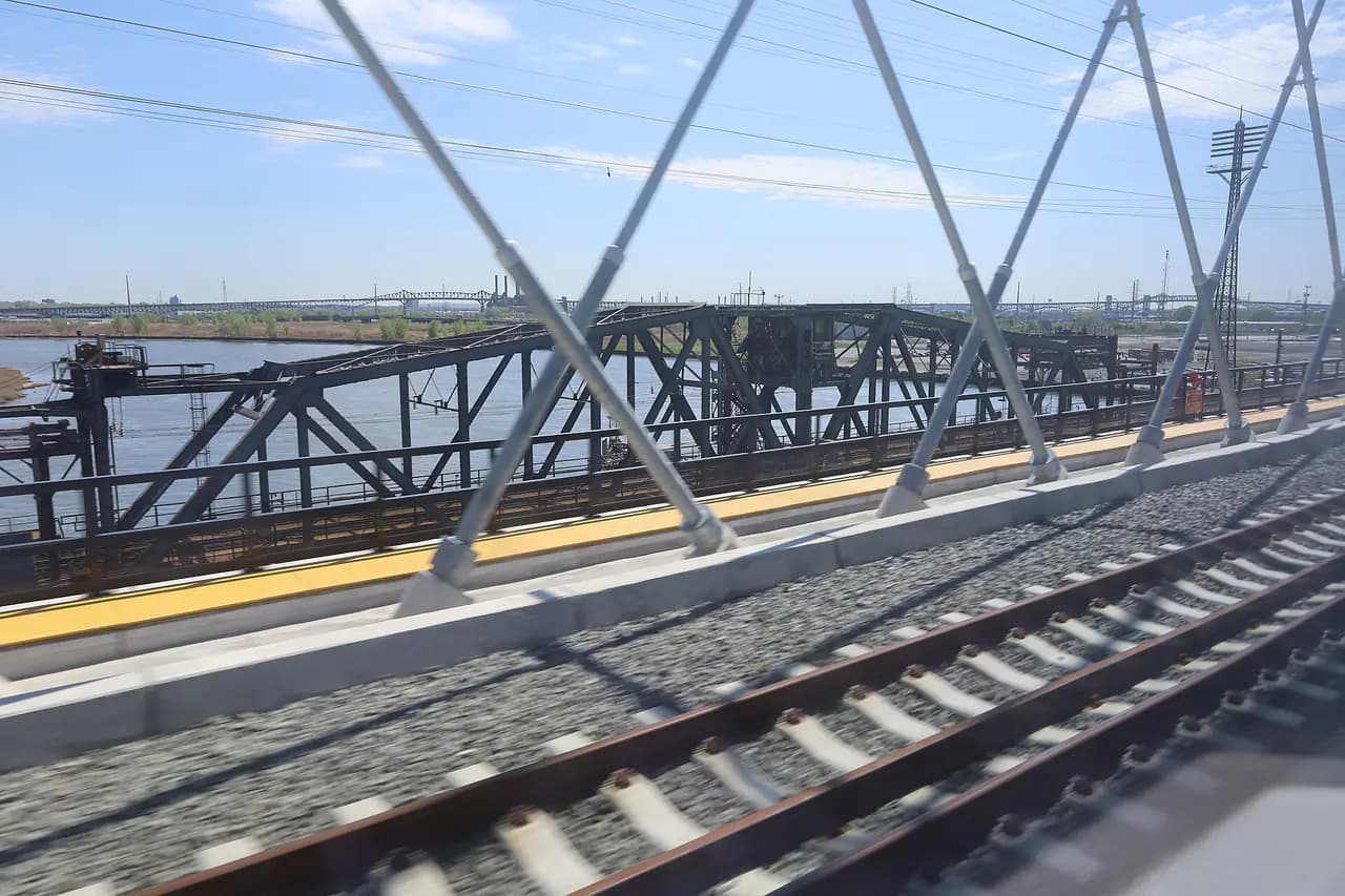 The old steel Portal swing bridge over the Hackensack River, seen through the cables of the new Portal North Bridge from a passing train