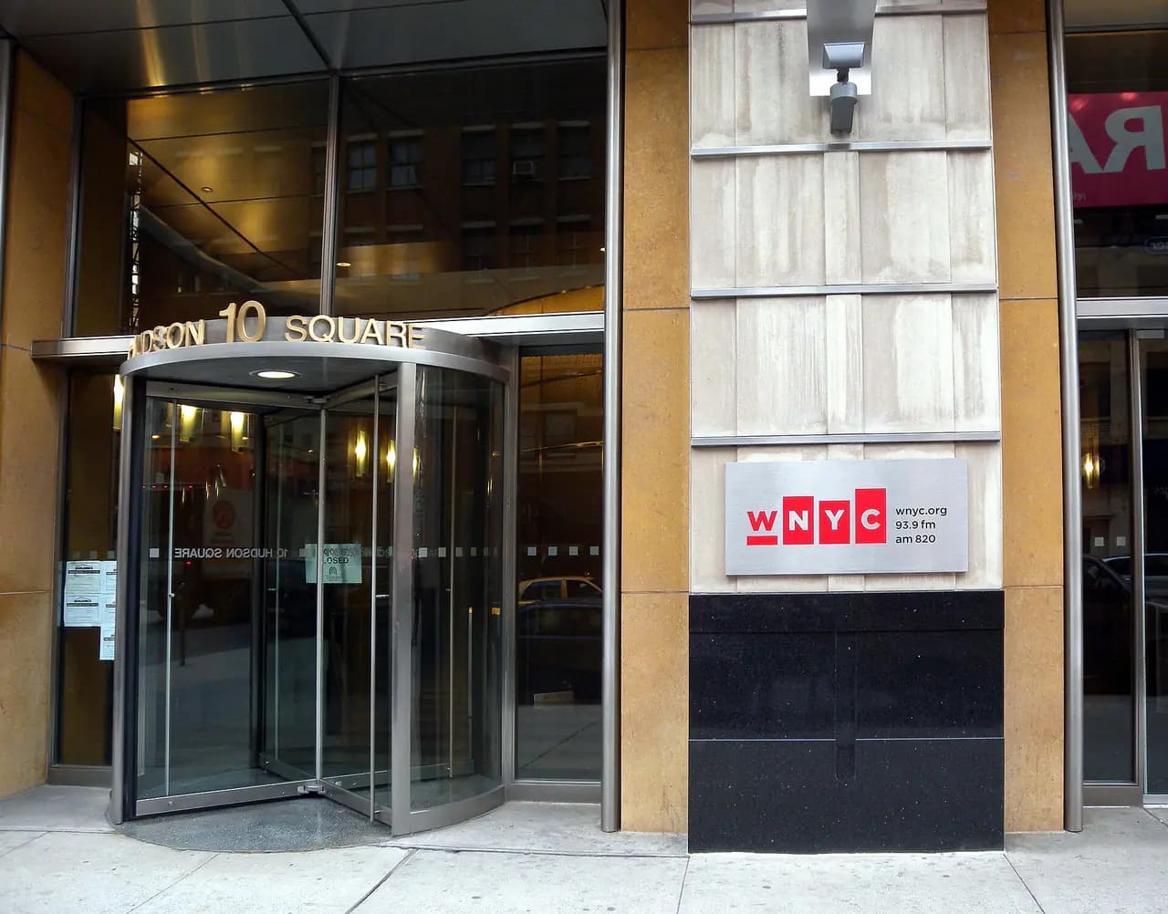 WNYC sign beside the revolving-door entrance of 160 Varick Street in Hudson Square