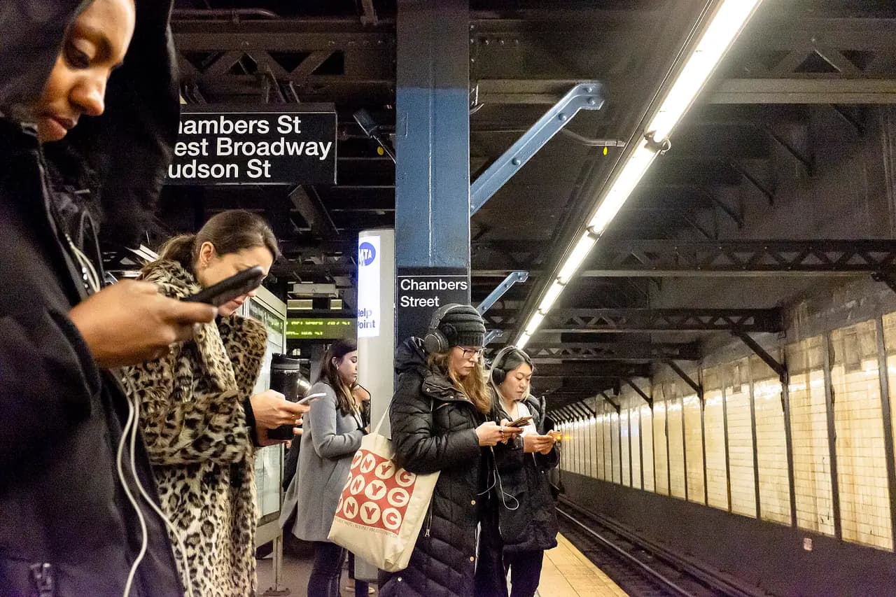 Commuters looking at their smartphones on the Chambers Street subway platform in Lower Manhattan