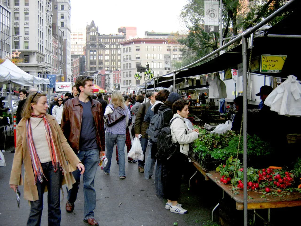 Shoppers browse produce stands under white tents at the Union Square farmers market in Manhattan
