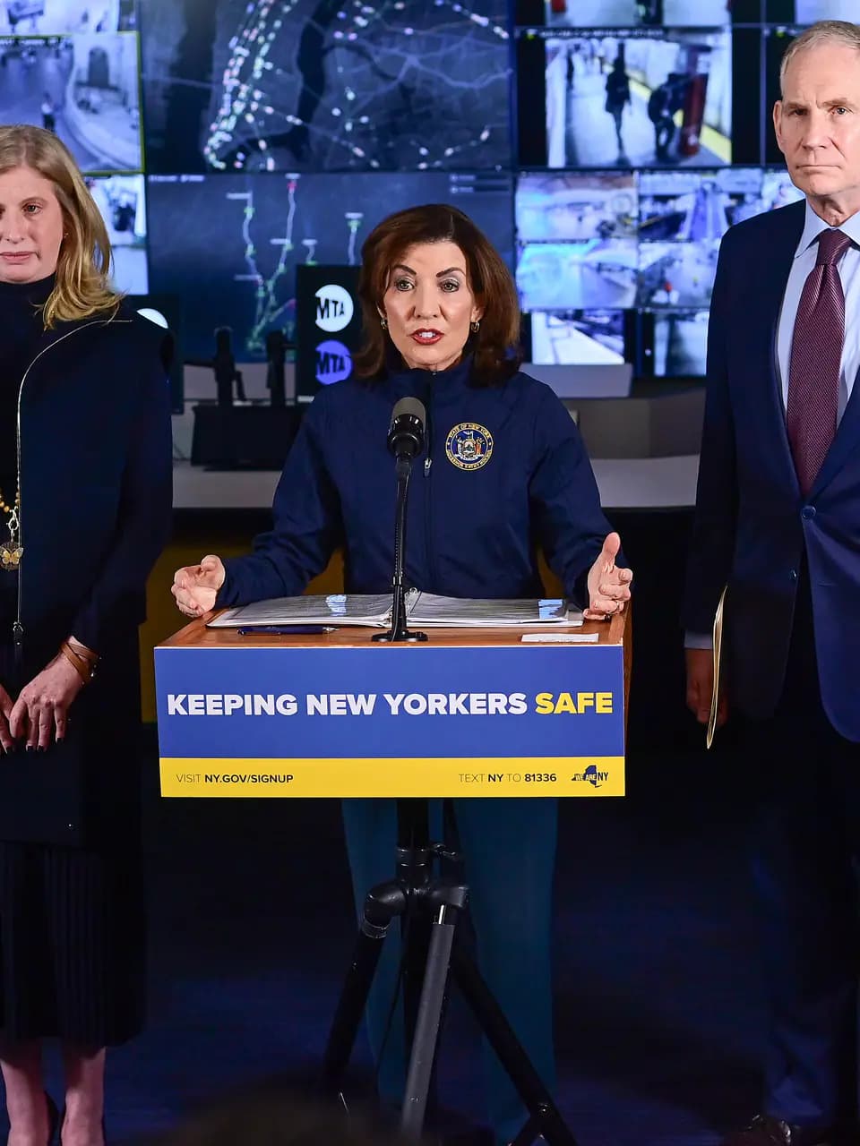 Gov. Kathy Hochul speaking at a lectern with her hands open
