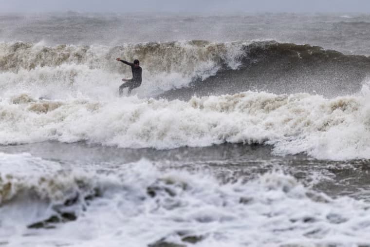 A surfer rides waves created by the nor'easter at Rockaway Beach in Queens, N.Y., on Sunday.