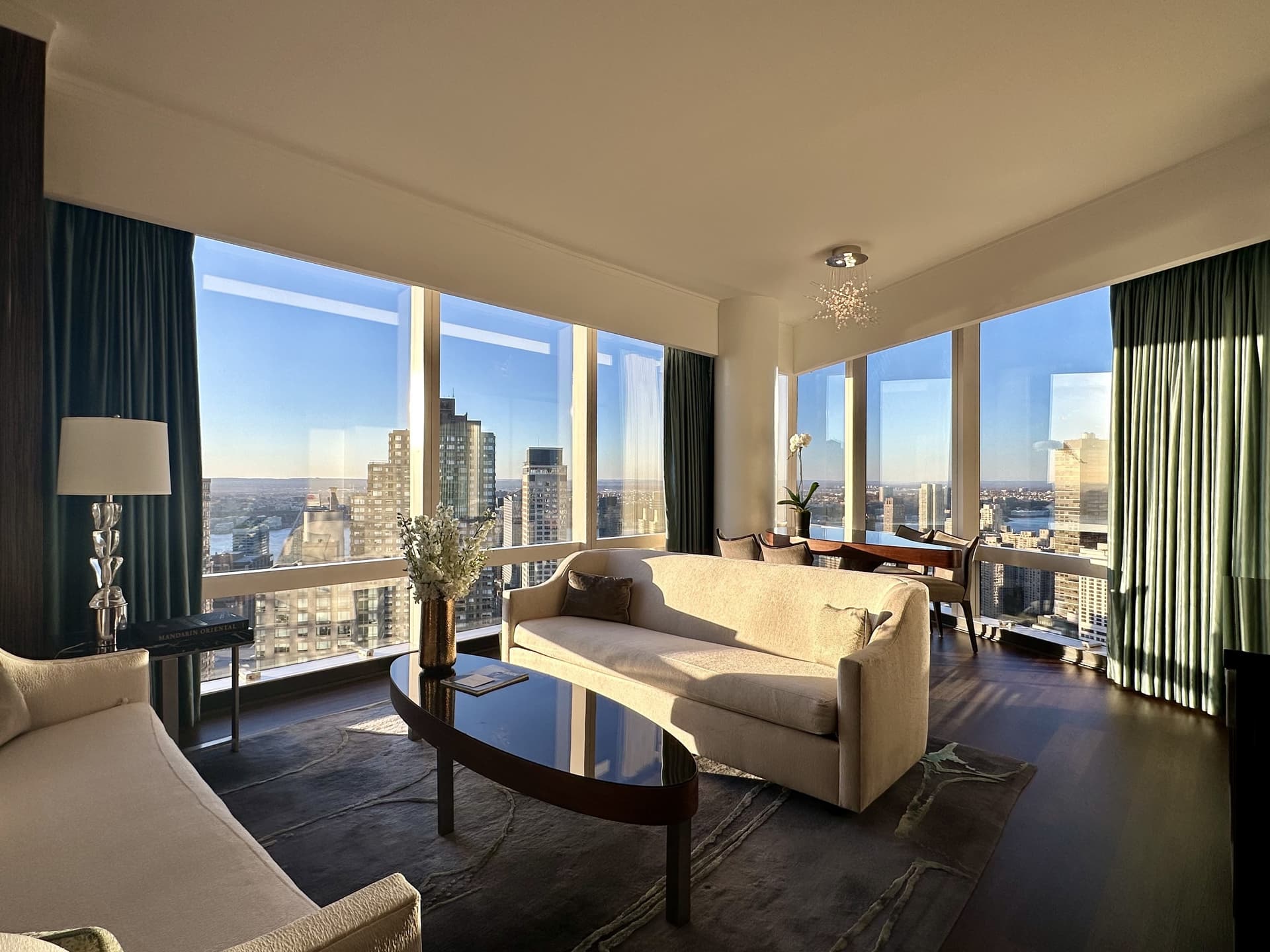 A hotel suite with couches and a table in front of skyline views.