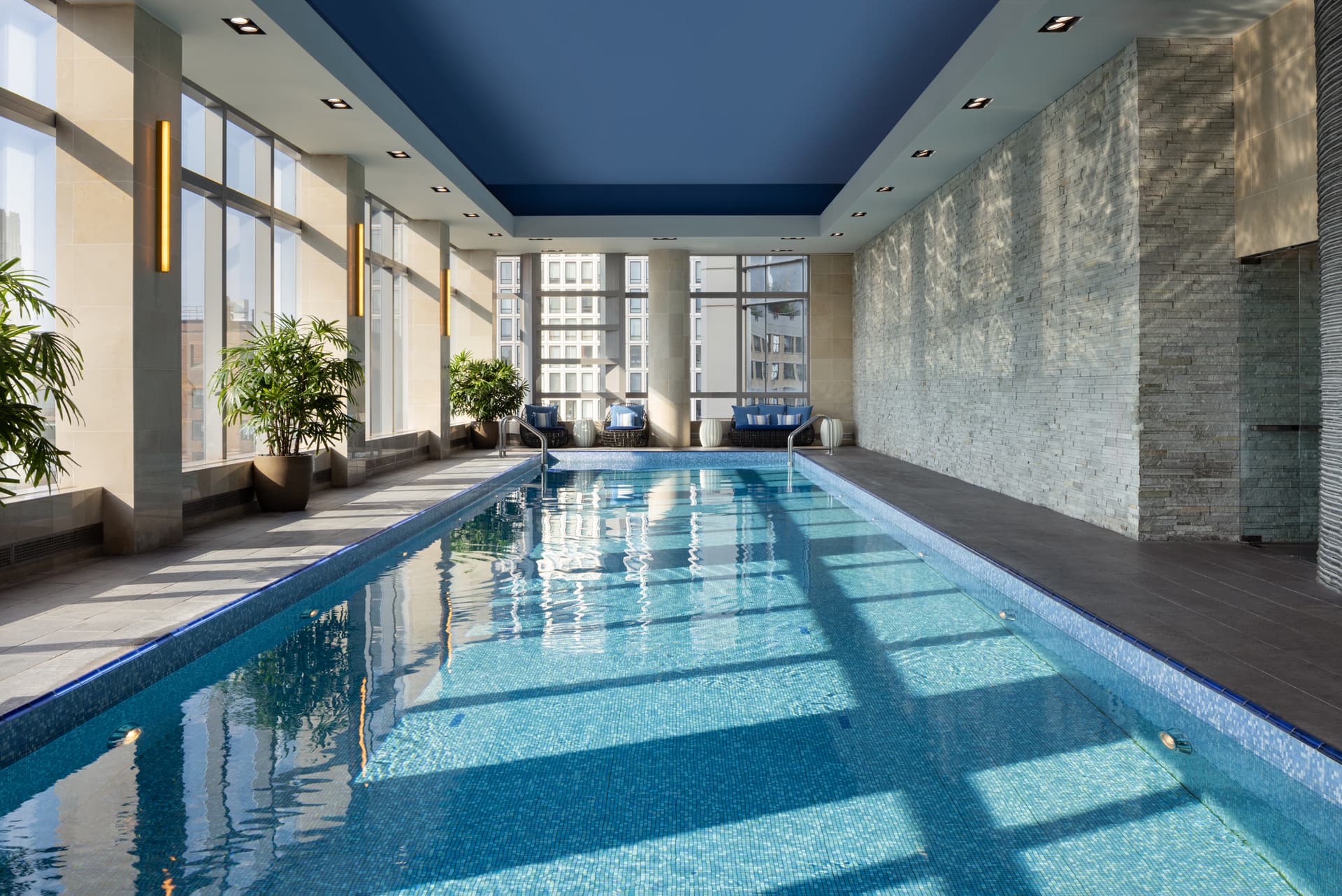 A swimming pool with bright light streaming into the windows.