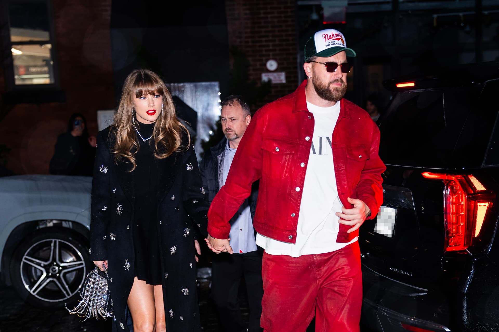 Taylor Swift and Travis Kelce holding hands.