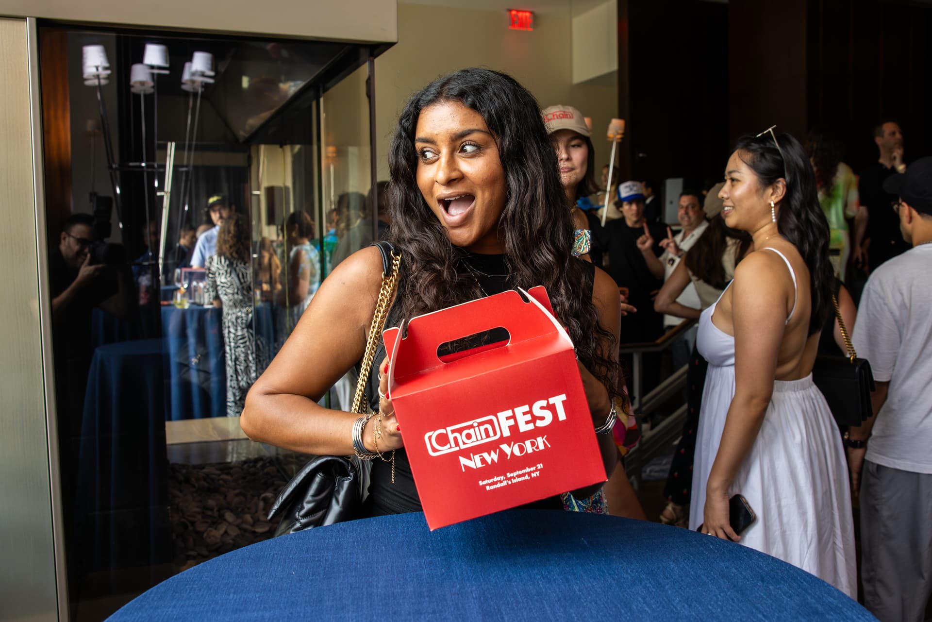 A woman holding a red takeout box that says chainfest